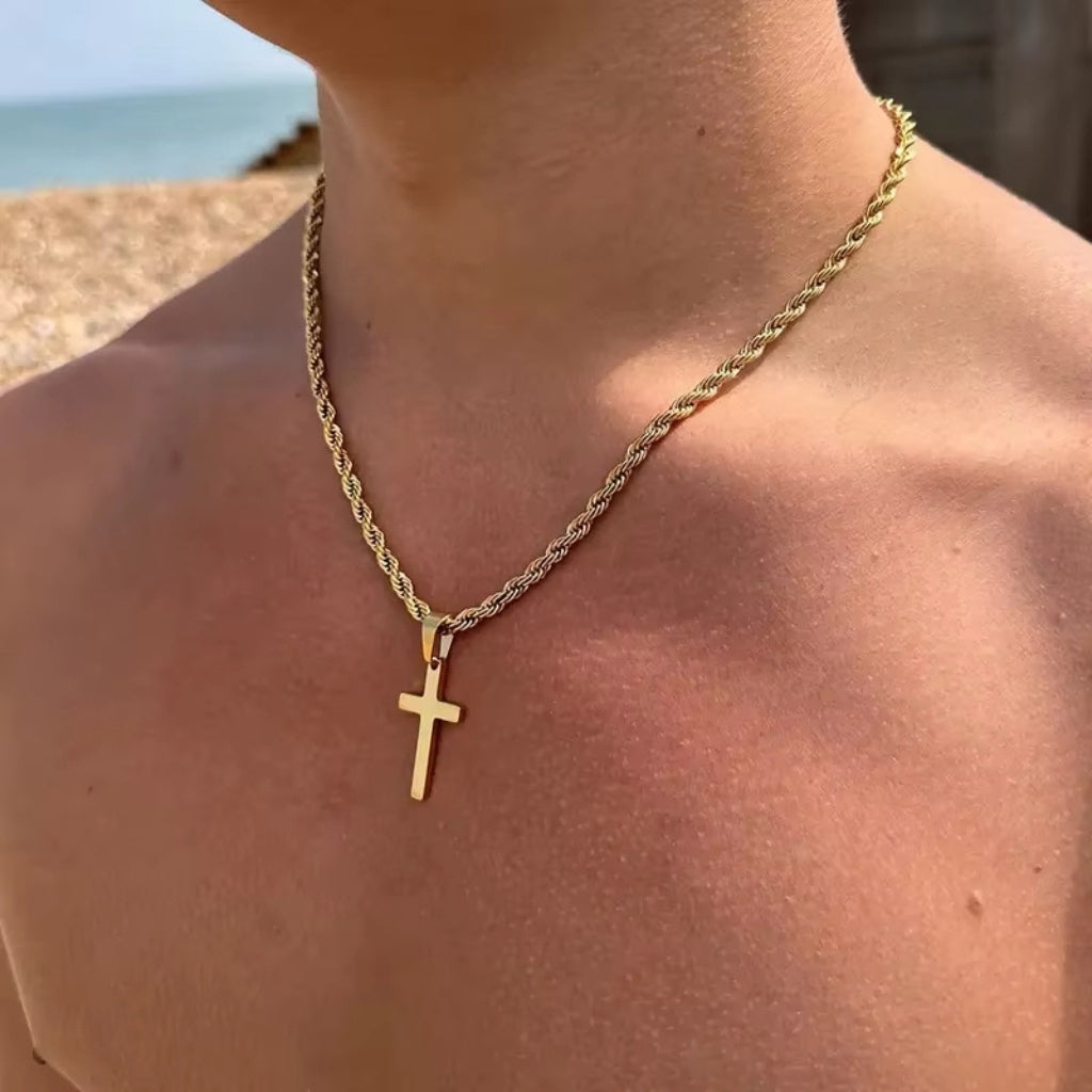 Homem usando colar de cruz dourado com corrente torcida grossa na praia.