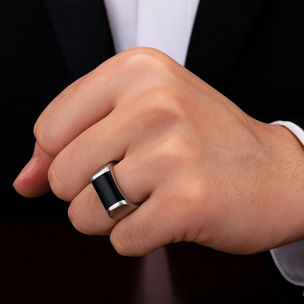 Homem usando anel masculino robusto de aço com detalhe preto na mão.