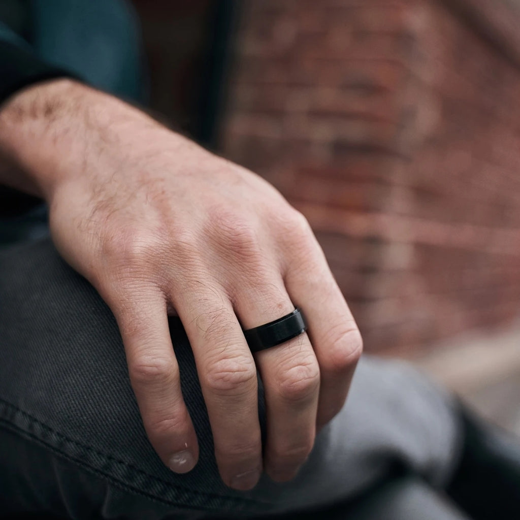 Homem usando anel de titânio preto leve e moderno na mão.