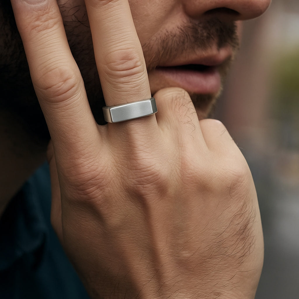 Homem usando anel de barra (bar signet) prateado fosco no dedo anelar.