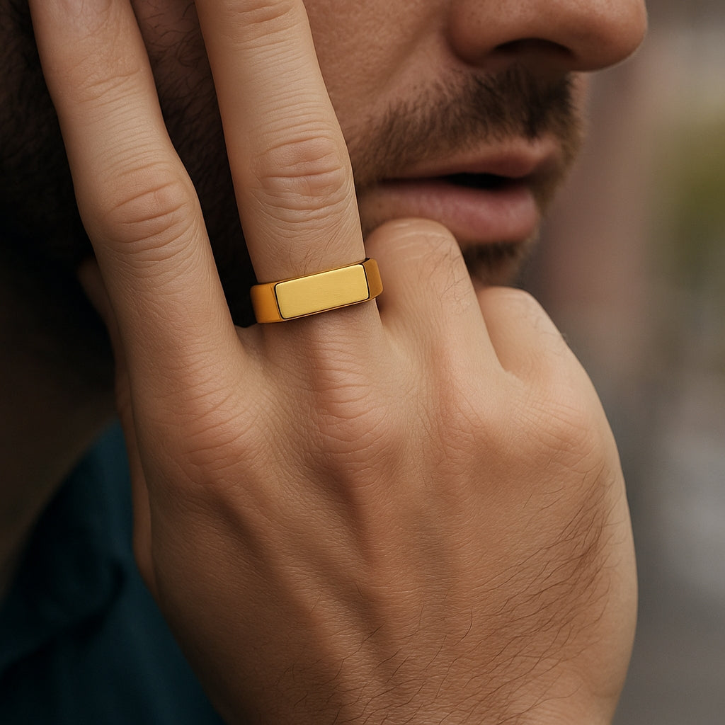 Homem usando anel de sinete dourado quadrado no dedo indicador.