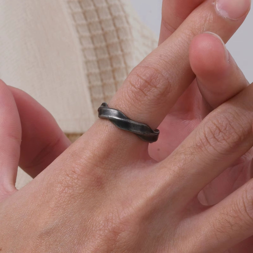 Homem usando anel de aço com design orgânico forjado estilo vintage.