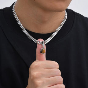 Homem usando colar de corrente prateada grossa com pingente retangular de pedra marrom Lucky.