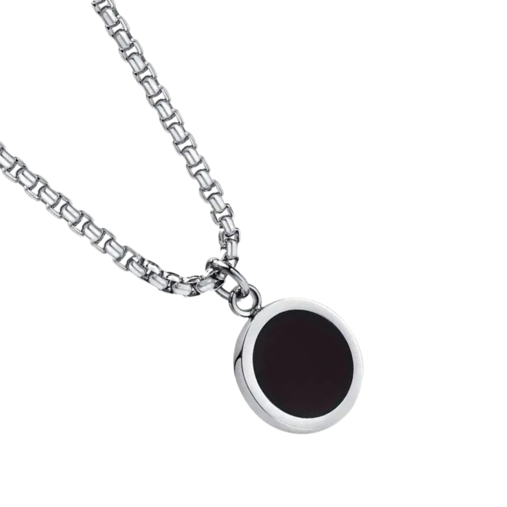 Detalhe do pingente redondo preto com borda prateada do colar masculino Broni.