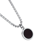 Detalhe do pingente redondo preto com borda prateada do colar masculino Broni.