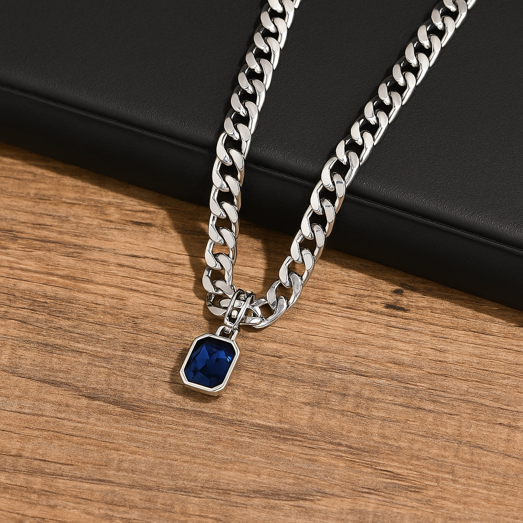 Colar masculino prateado modelo Irsina com pedra de zircônia azul escuro Classiatti em cima de uma caixa preta e fundo de madeira