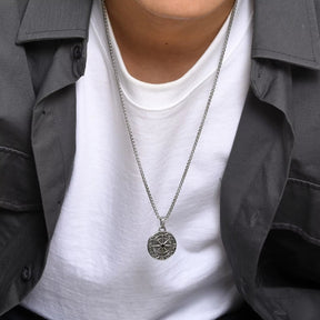 Homem usando colar com pingente de rosa dos ventos estilo vintage na camiseta branca.