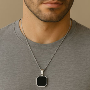 Homem usando colar prateado com pingente geométrico preto de 8 lados (octógono).