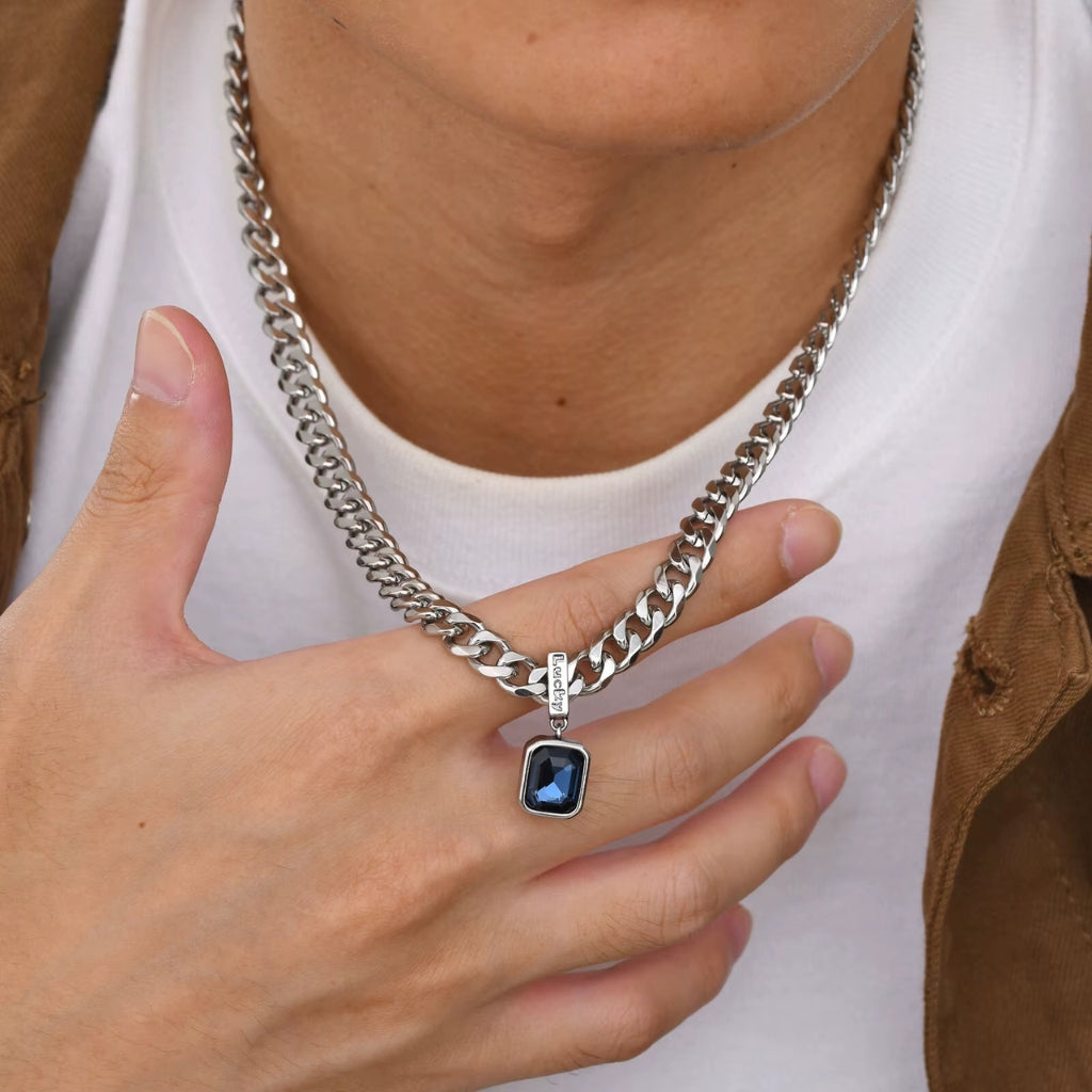 Homem usando Colar masculino prateado modelo Irsina com pedra de zircônia azul escuro Classiatti enquanto o levanta com a mão
