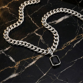 Colar masculino preto modelo Irsina Black em aço inoxidável da Classiatti em cima de uma pedra preta com detalhes brancos e amarelos