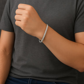 Homem usando pulseira de malha fita prateada lisa no pulso.