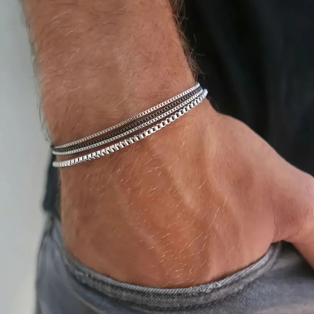 Homem usando mix de pulseiras finas geométricas de aço no pulso.