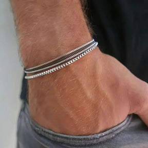 Homem usando mix de pulseiras finas geométricas de aço no pulso.