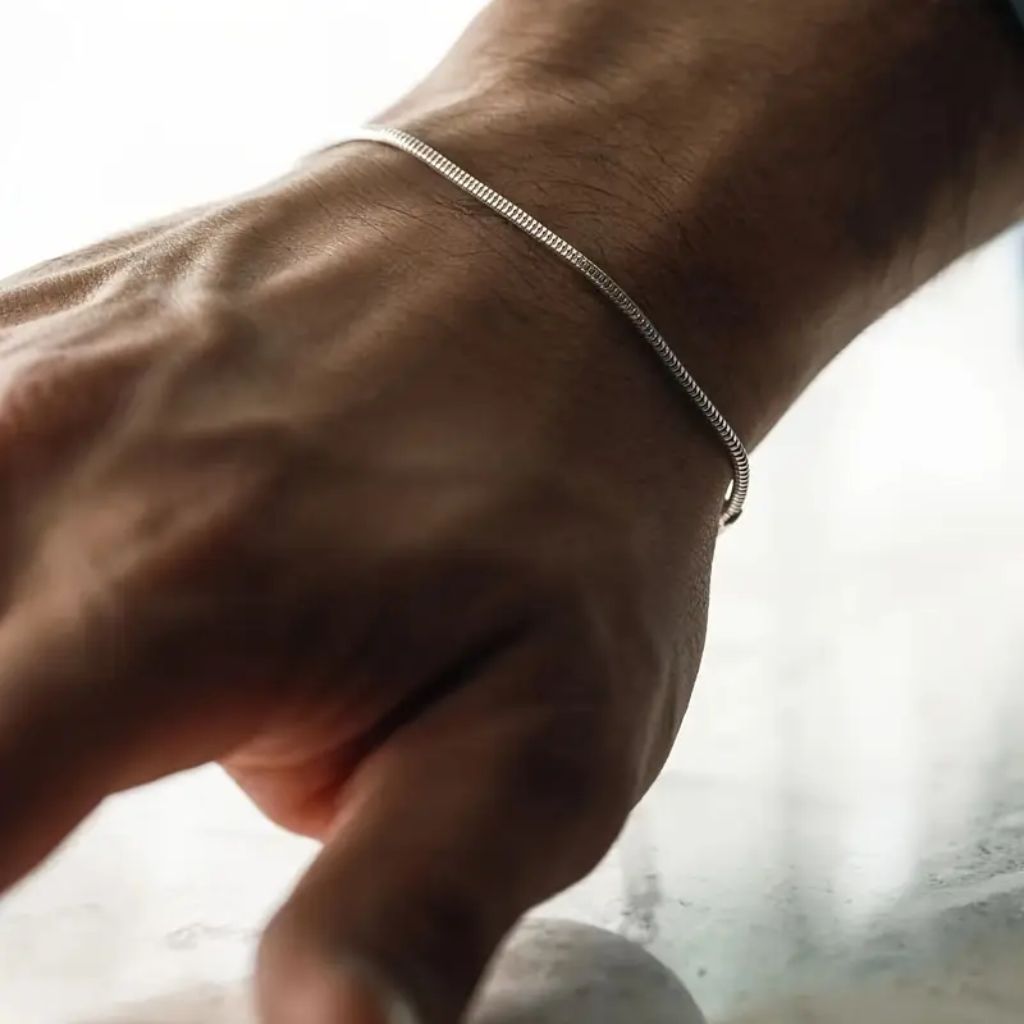Homem usando pulseira fina de fio redondo prateado (estilo snake) no pulso detalhes