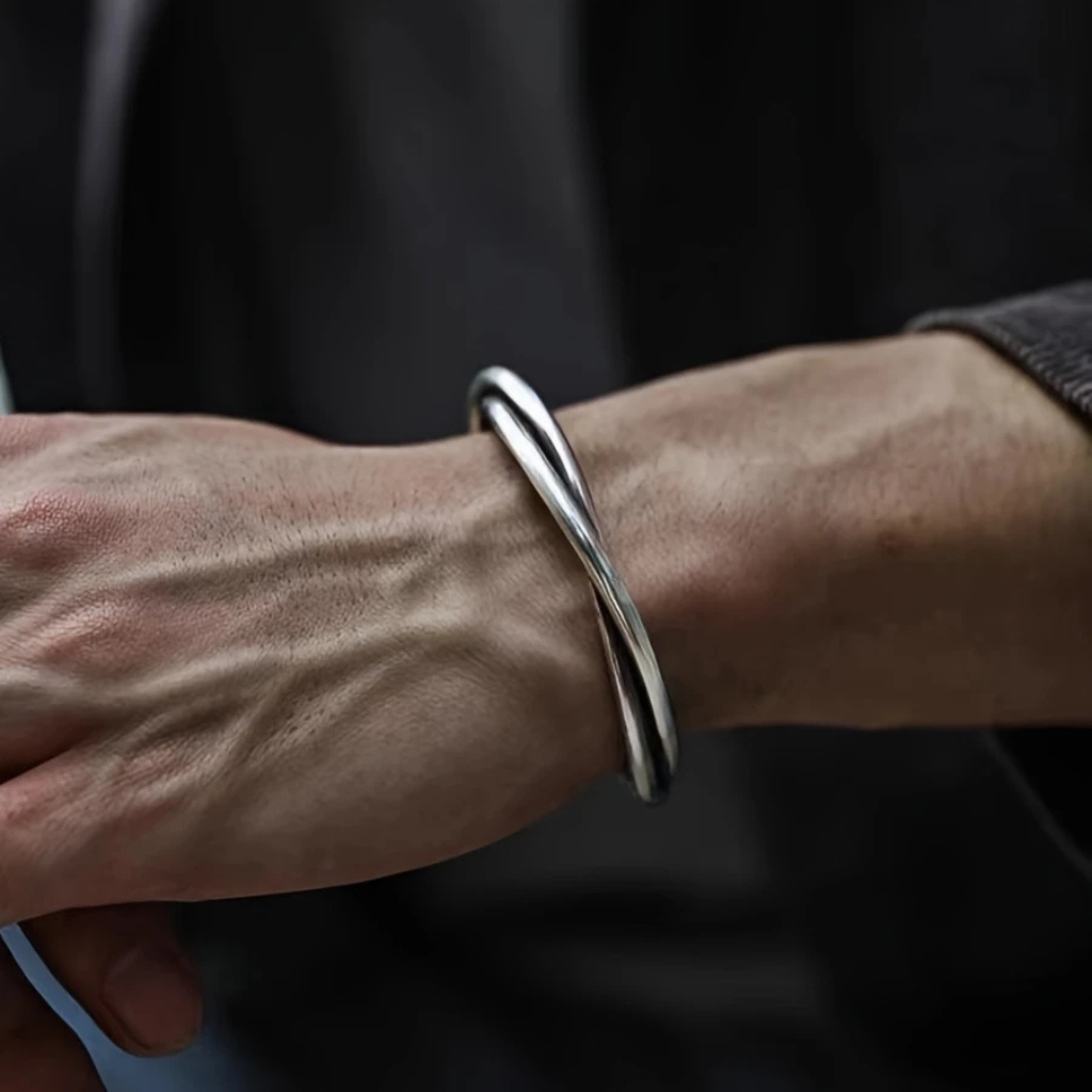 Braço masculino usando bracelete prateado ajustável estilo torcido no pulso.