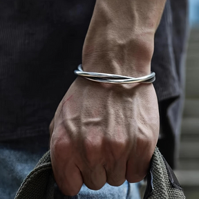 Homem usando bracelete prateado ajustável estilo torcido no pulso.