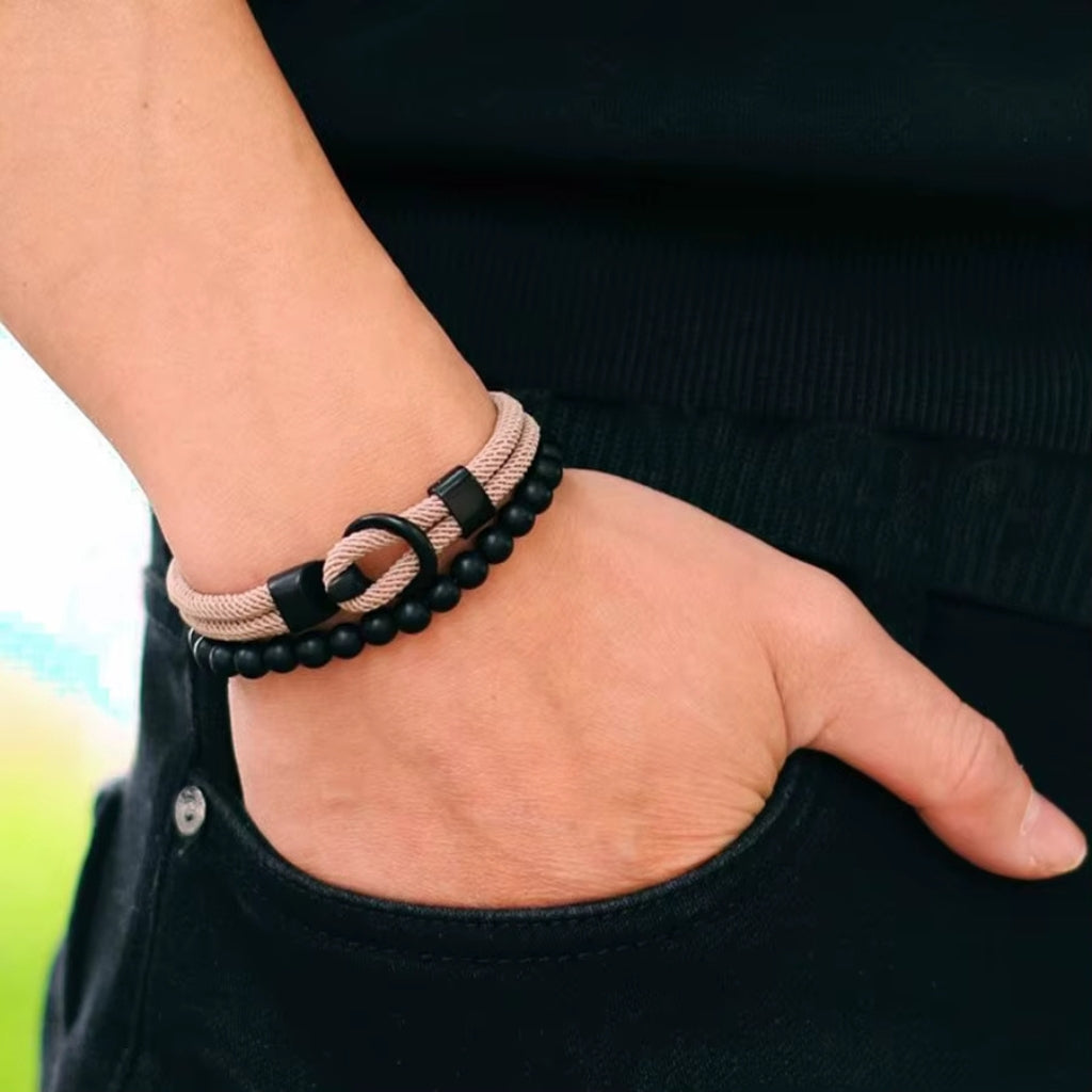 Homem usando mix de pulseiras bege e preto estilo casual moderno.